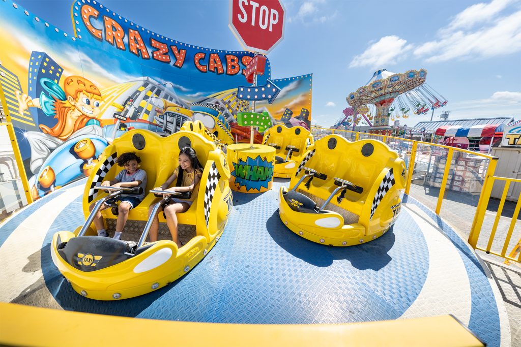 Two children enjoying a thrilling ride in a car at an amusement park, filled with excitement and joy.