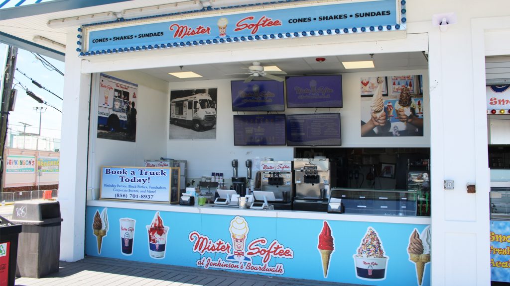 A Mister Softee ice cream stand at Jenkinson's Boardwalk, featuring machines, digital menu boards, and colorful signage of cones, shakes, and sundaes.