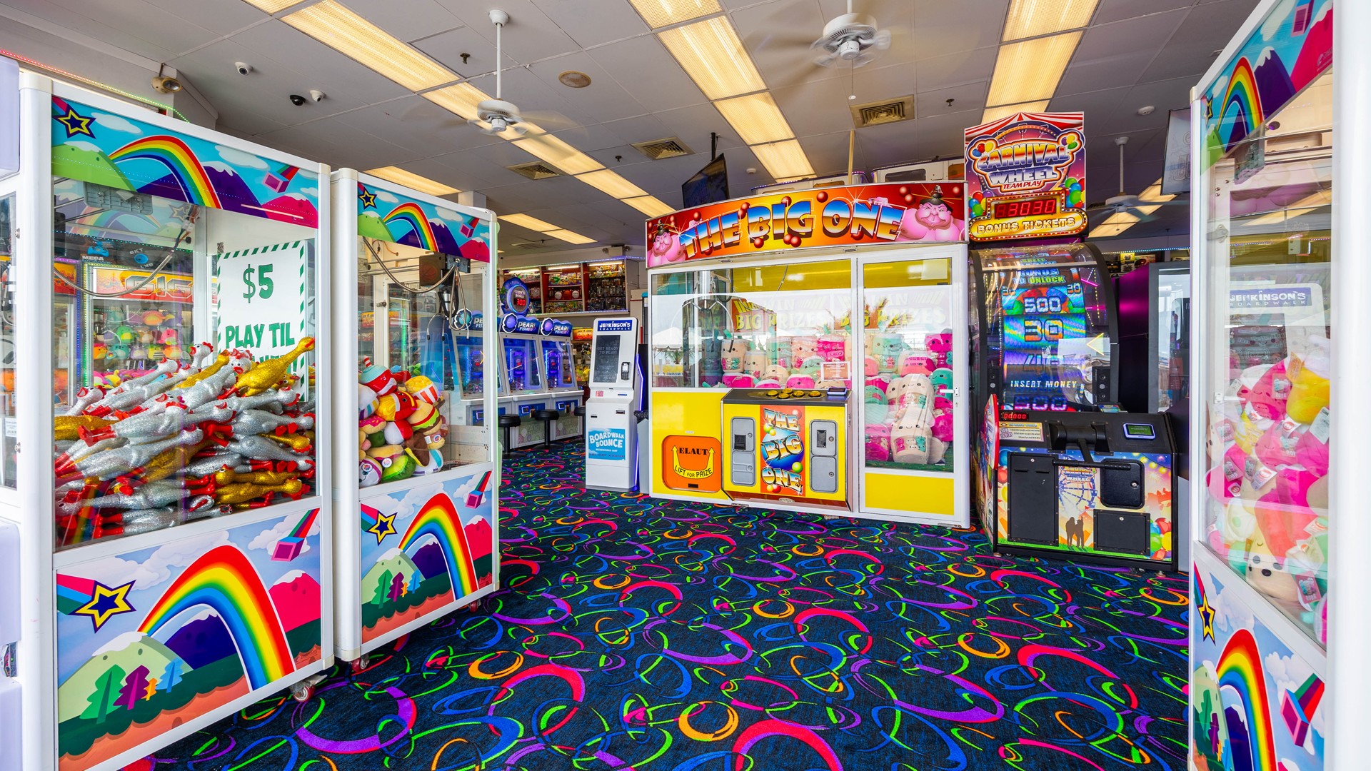 Colorful arcade interior featuring claw machines, prize games, and bright patterned carpet at Jenkinson’s Boardwalk.