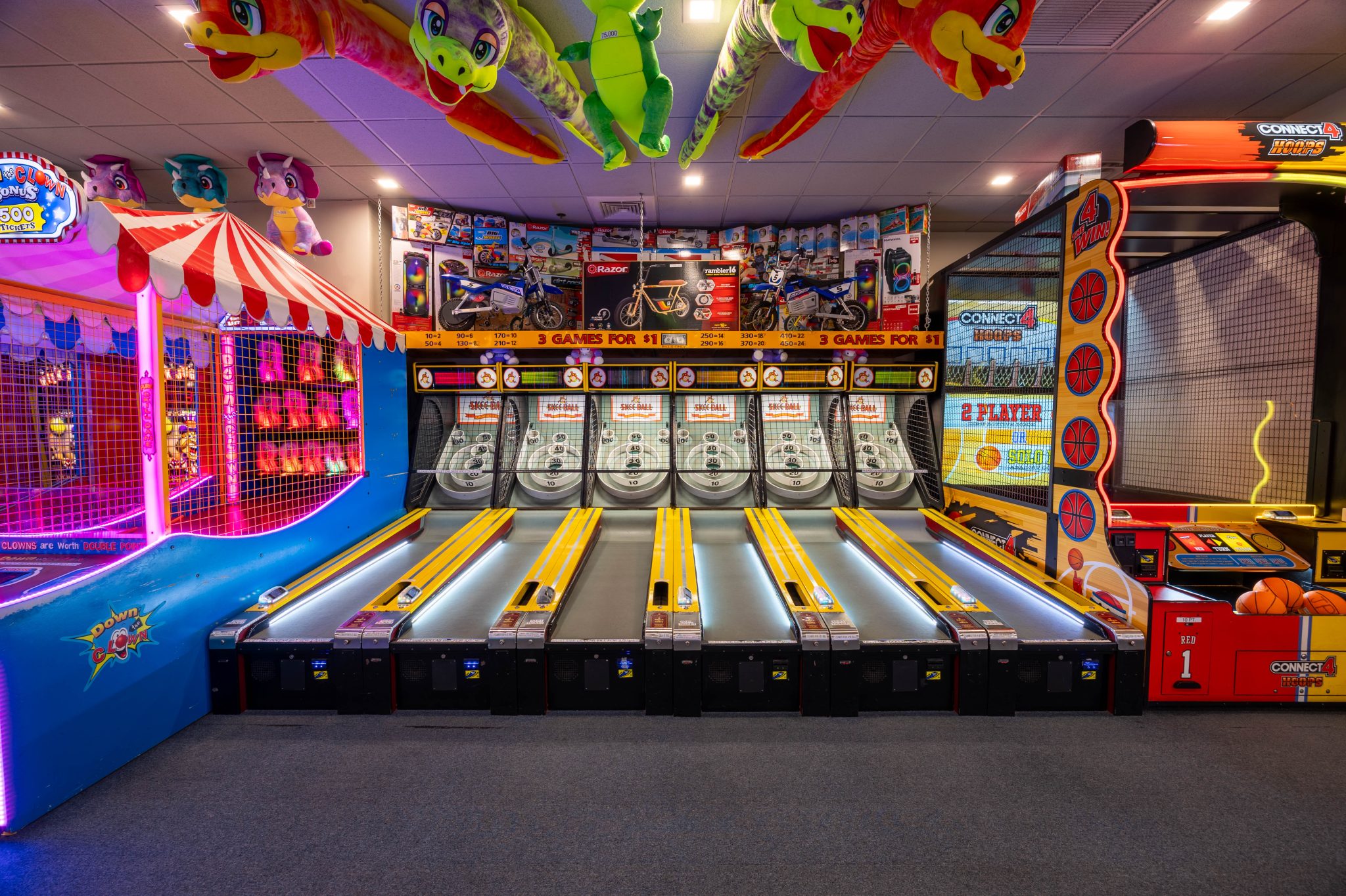 Indoor arcade featuring skee-ball lanes, basketball games, and colorful prize displays at Jenkinson’s Boardwalk.